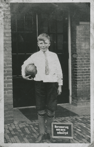876456 Portret van Johannes Hendrikus ('Joop') de Winter, bij de deur van een onbekende school te Utrecht, met een ...